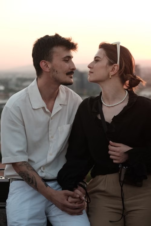 Claire and Adrien sitting together at sunset, looking at each other